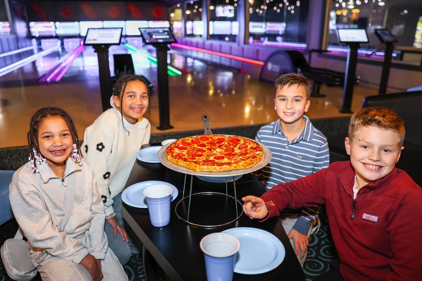 Kids with pizza by the bowling lanes