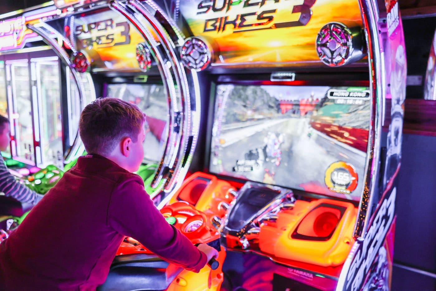 Kid playing a motorcycle arcade game