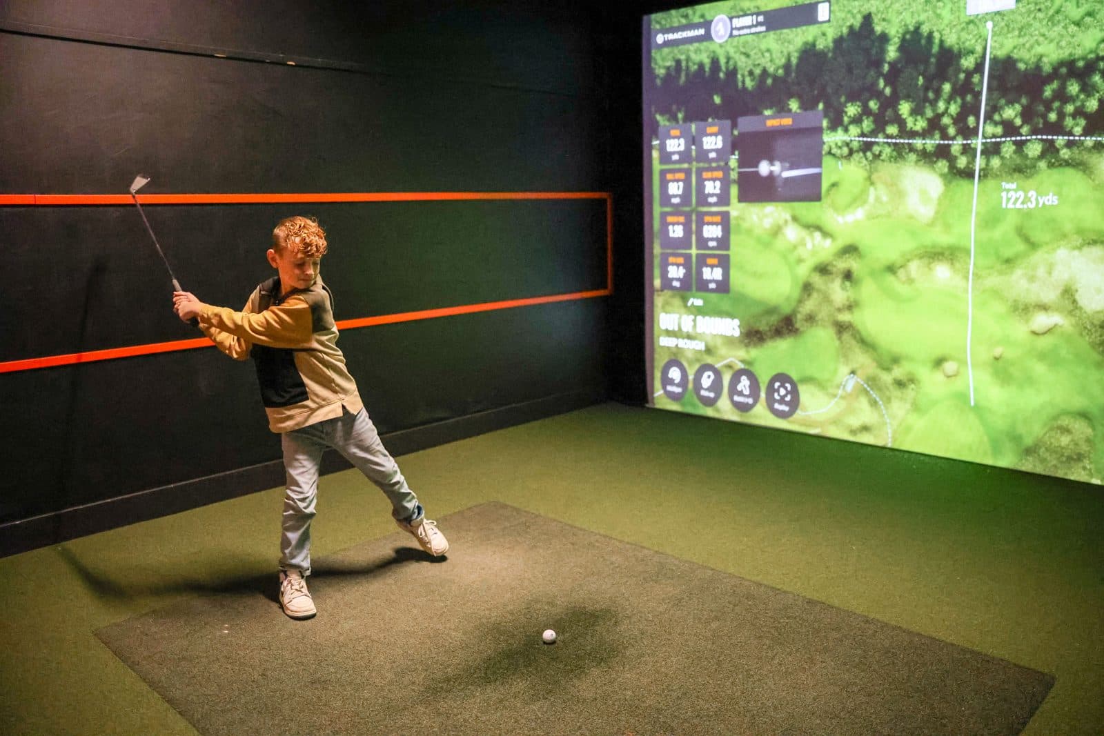 Birthday guest taking a swing on the golf simulator